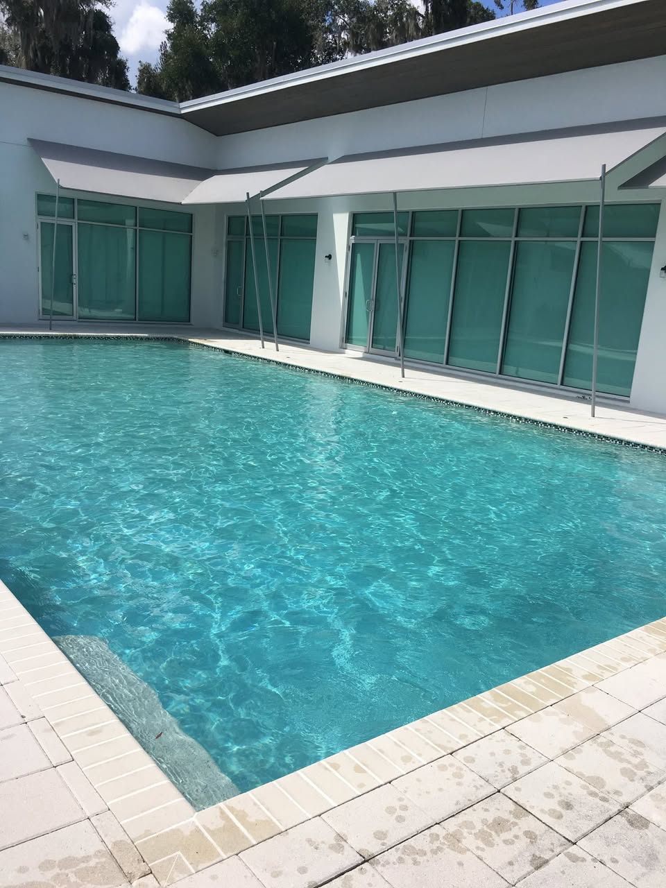 Large modern Orlando luxury pool with crystal clear turquoise water and travertine deck