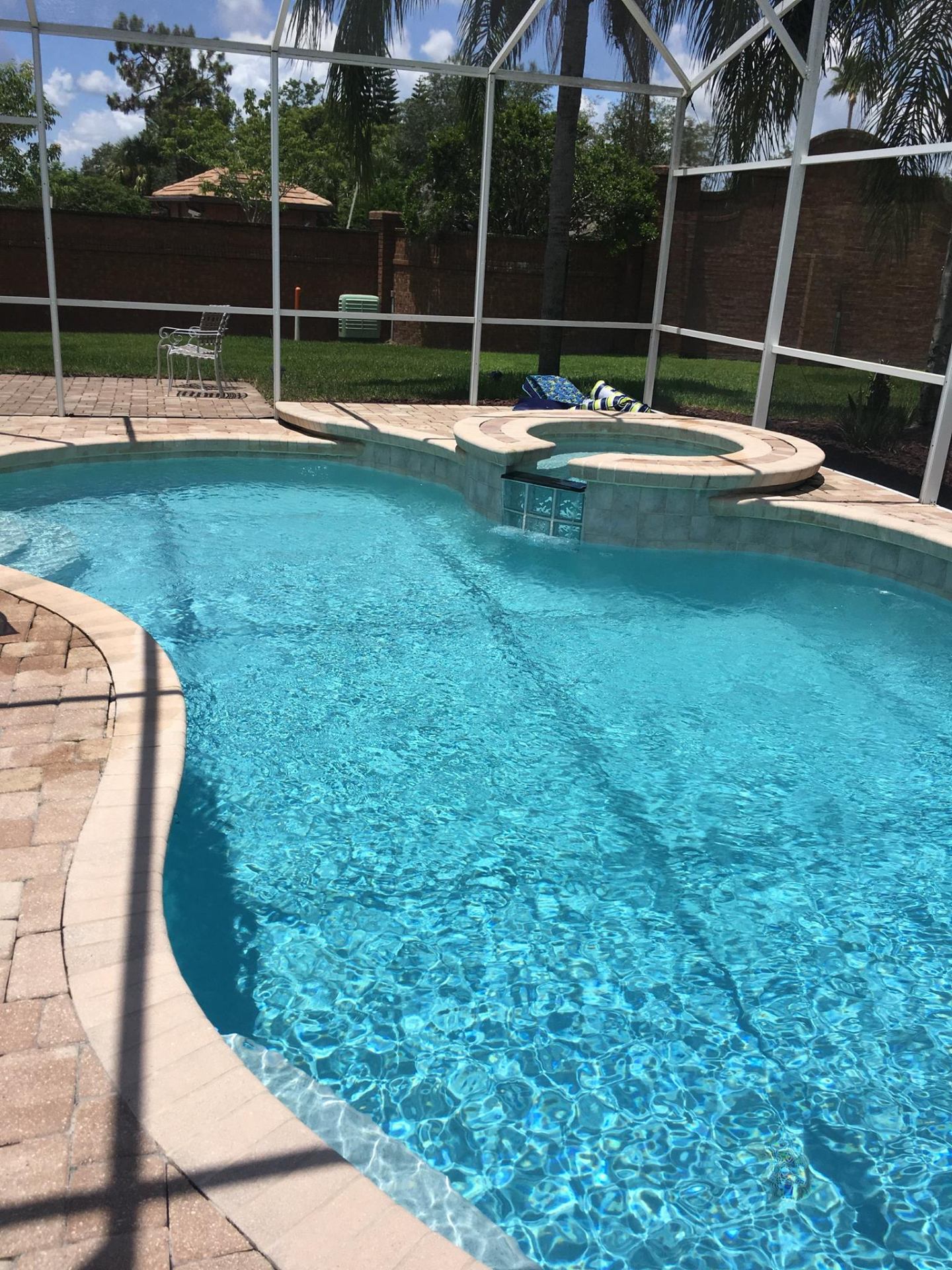 Crystal clear Avalon Park, FL freeform pool with raised spa and paver deck after weekly Sunny Clean Pool service