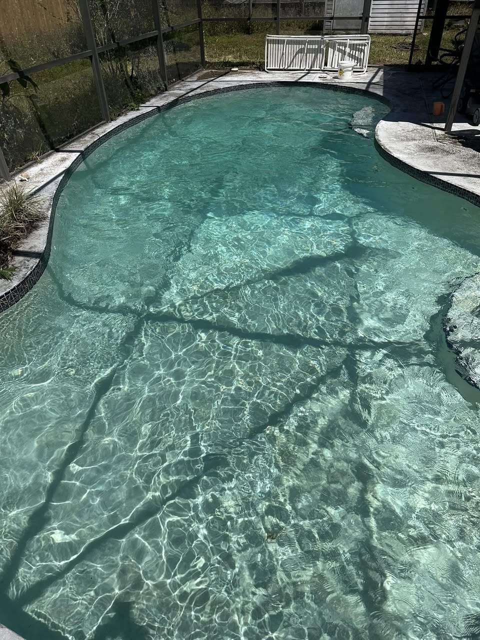 Sunny Clean Pool technician performing weekly pool service on a screened backyard pool in Wedgefield, FL 32833