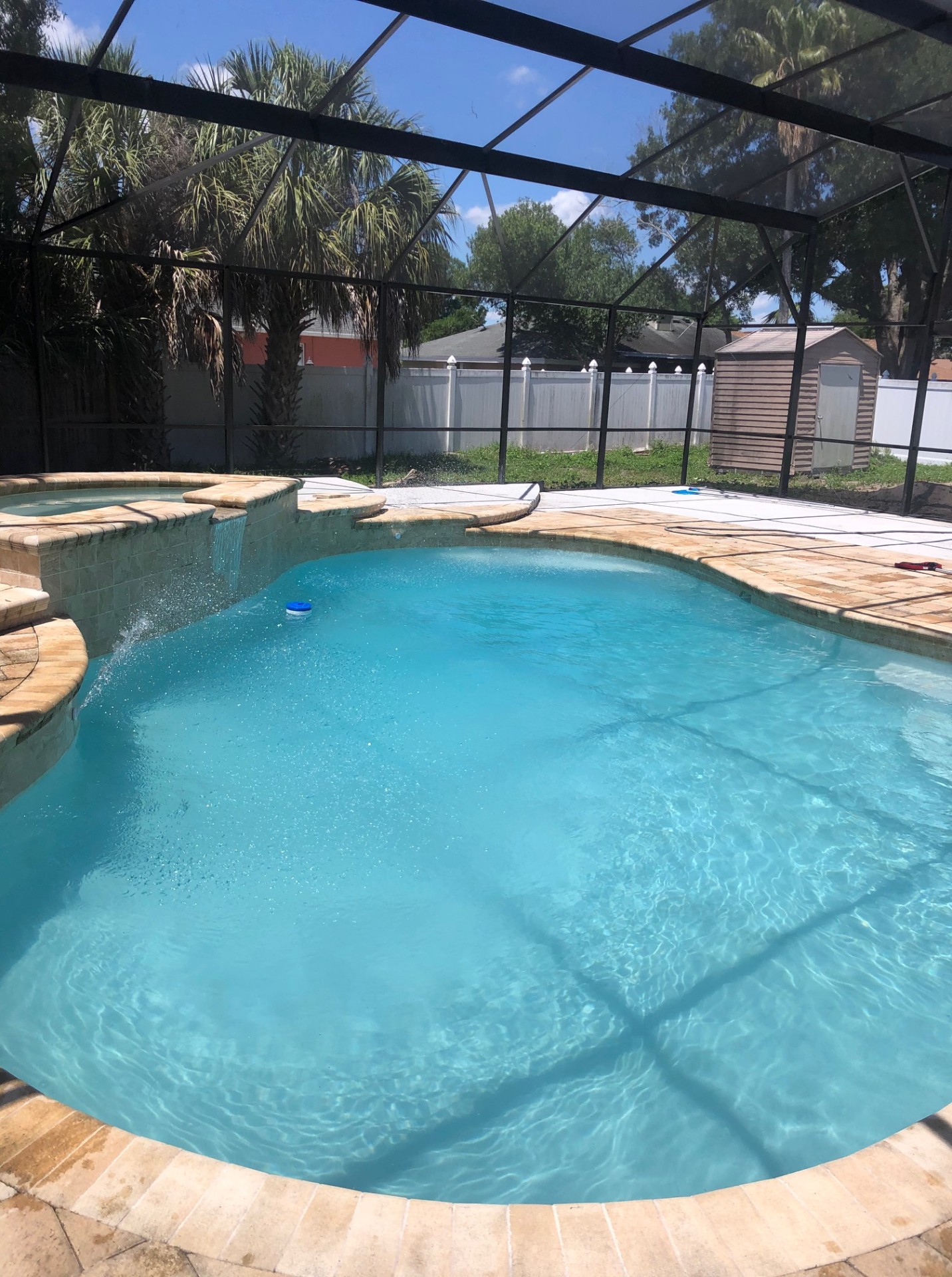 Sparkling clean kidney-shaped Orlando pool with spillover spa and travertine deck after professional service